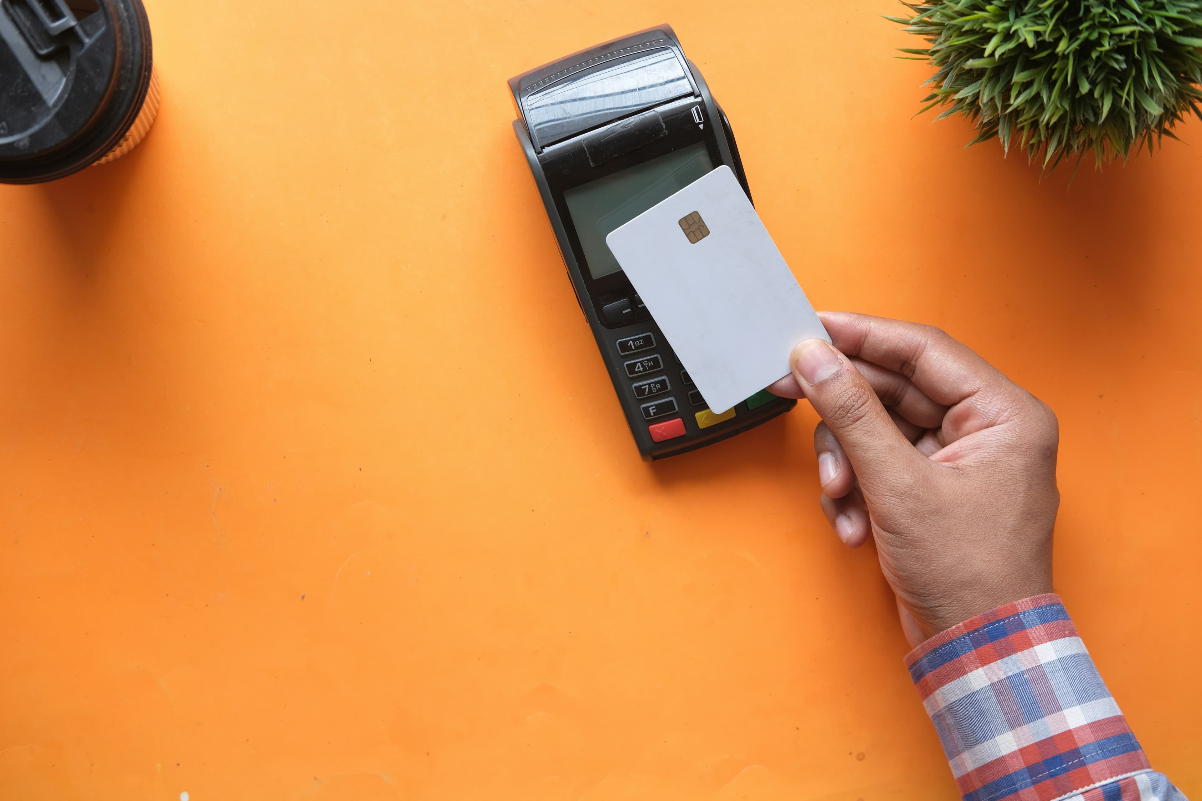 Credit card terminal with card tap on orange background